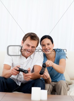 Excited couple playing video games together on the sofa