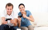 Excited woman playing video games with her boyfriend on the sofa