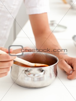 Close up of a man and woman tasting a sauce in the kitchen