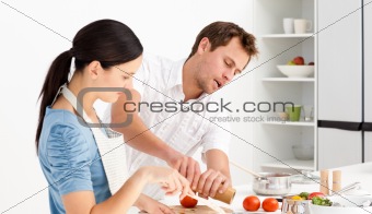 Man putting salt and pepper while his girlfriend stirring 
