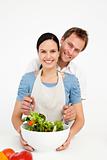 Happy man mixing a salad with his girlfriend in the kitchen