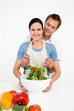 Happy woman mixing a salad with her boyfriend in the kitchen