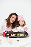 Adorable mother and daughter showing a plate with biscuits