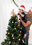 Cute son decorating the christmas tree with his father