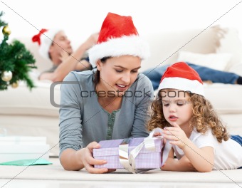 Mother and daughter unwrapping a present lying on the floor