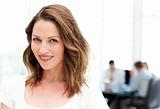 Relaxed businesswoman standing in front of her team while workin