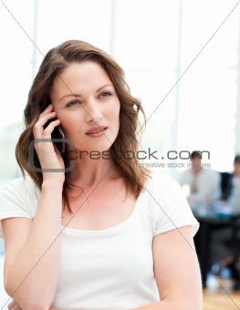 Pensive businesswoman on the phone while her team is working