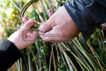 Man teaching child making a wicker basket