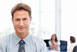 Relaxed businessman posing in front of his team while working 
