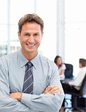 Happy businessman standing in front of his team while working 
