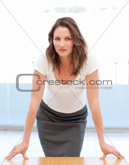 Confident businesswoman posing leaning on a table