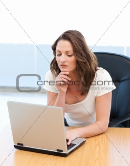 Pensive businesswoman working on laptop at a table