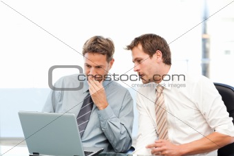 Two concentrated businessmen working together on a laptop