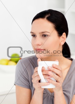 Quiet woman drinking her coffee in the kitchen 