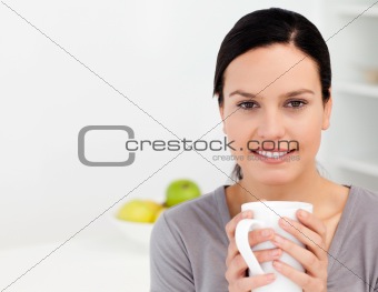 Lovely woman holding a cup of coffee while relaxing in the kitchen