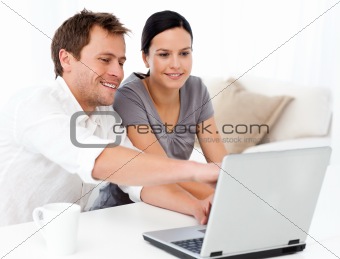 Cute man showing something on the laptop screen to his girlfriend