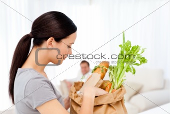 Man relaxing on the sofa while his girlfriend tidying the kitchen