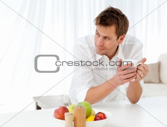 Pensive man drinking coffee standing at a table
