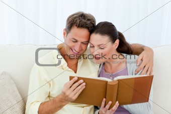 Attentive man and woman looking at a photo album on the sofa