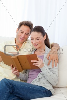 Cute couple looking at a photo album on the sofa