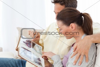 Lovely couple looking at pictures on a photo album on the sofa