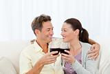 Passionate couple drinking red wine while relaxing on the sofa