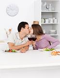 Young couple kissing with red wine in their hands during lunch 
