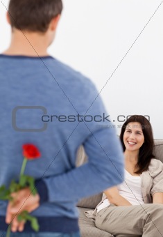Enamored man hiding a flower behind his back for his girlfriend