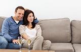 Relaxed couple watching television while drinking champagne
