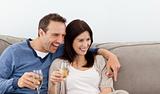 Cheerful couple drinking champagne on the sofa