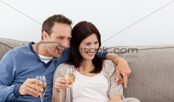 Cheerful couple drinking champagne on the sofa