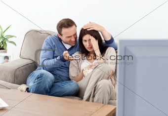 Scared woman watching a horror movie with her boyfriend