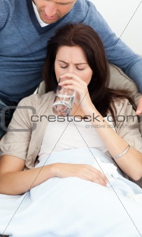 Sick woman drinking water lying on the sofa