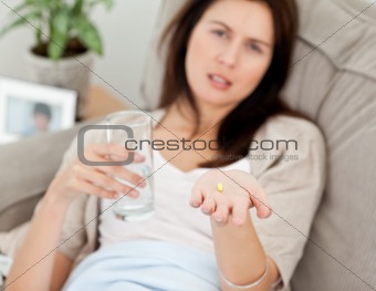 Close up of a woman taking her medicine on the sofa