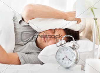 Frustrated man listening to his alarm clock