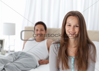 Pretty girl sitting on the edge of her bed with her boyfriend