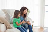 Attentive mother encouraging her daughter playing video games