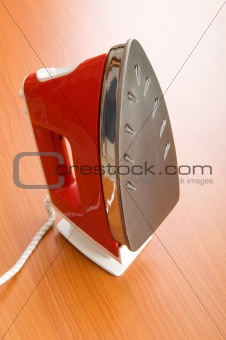 Modern electric iron on the wooden background