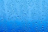 closeup of waterdrops after rain on glass roof reflecting blue sky