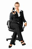 Smiling modern business woman sitting on chair and showing mobile phone in hand
