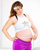 Worried beautiful pregnant woman measuring her tummy
