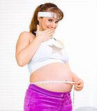 Confused beautiful pregnant woman measuring her belly
