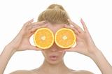 Young woman holds halves of oranges before eyes