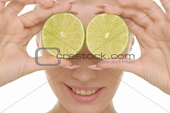 Young woman holds halves of lime before eyes