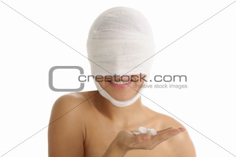 Woman with bandaged head with tablets on palm