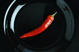 Red burning pepper on a black plate