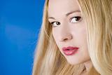 Beautiful young woman with red lips and blond long hair against the blue background.