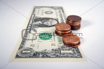 Pennies on the Dollar - one dollar bill with small stacks of pennies on top on a white background.