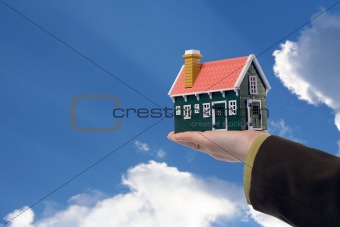 House in woman hand and sky