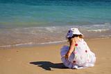 Little girl crouching on the beach
